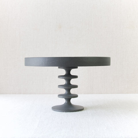 Profile image of a Robert Welch fruit stand. The item is cast iron. The finish is raw meaning the footed plate is black in colour and texture like smooth concrete.