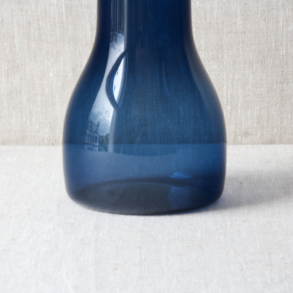 A indigo blue carafe by Kaj Franck. The bell-bottomed shape of the lower half of the Model 1615 pitcher creates a low centre of gravity, meaning it cannot be overturned easily. The bulbous organic body is also perfect for aerating wine. 