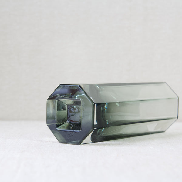 Low down image of a octagonal shaped glass vase laying down. This design is by Kaj Franck, one of the leading names in 20th century Scandinavian design. London based design gallery Art & Utility offer many pieces of Nordic design for sale with worldwide shipping.