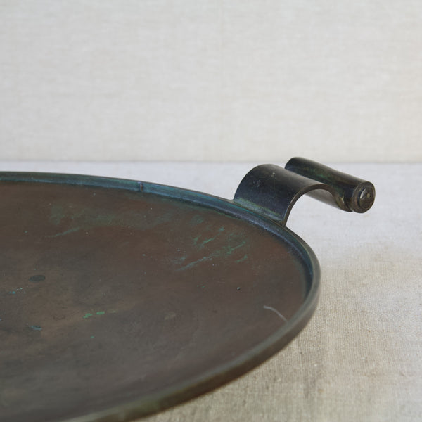 Top down image looking into the dish of a bronze platter or charger with scroll carrying handles. The design, by Einar & Sune Bäckström, is inspired by neoclassicism and art deco.