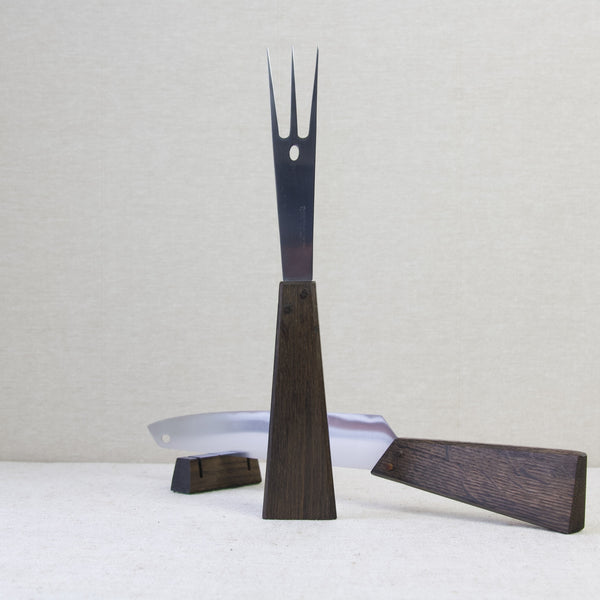 Head on shot showing a carving fork in stainless steel and black oak standing straight up. This Mid-twentieth century design is by Finnish designer Tapio Wirkkala. The carving set was designed by Hackman Oy, Finland.