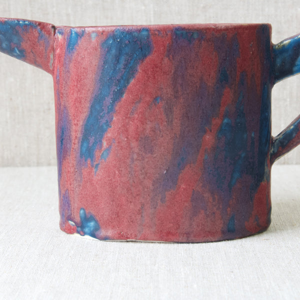 Head on shot of the main body of an Emmanuel Cooper jug. This surface is the perfect backdrop to Coopers outlandishly colourful experimental glaze which contains reds, pinks, purple, and blues.