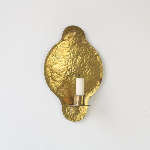 Unique hammered detailing on this brass wall sconce adds depth and character to any room.