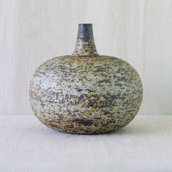 Annikki Hovisaari stoneware vase with iron-rich glaze settled into the pits and irregularities of its heavily textured chamotte surface.