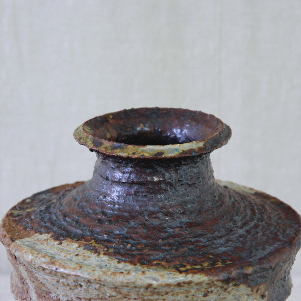 Detail of Annikki Hovisaari vase with expressive iron-rich glaze, dripping and pooling across the coarse chamotte clay body.