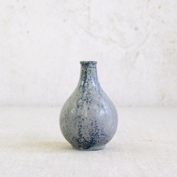 Small ceramic vase with blue speckled pattern on a light background. Danish studio pottery vase by Arne Bang Model 71 showing naturalistic glaze and early mid-20th-century Modernist style.