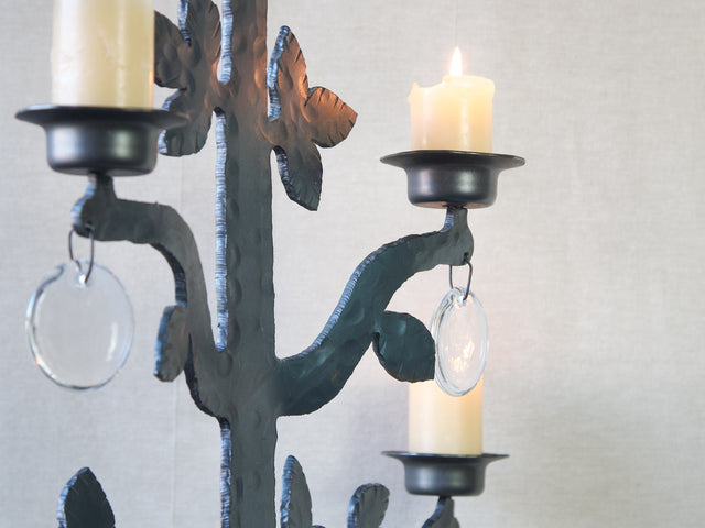 A detail mood shot of a black hand forged iron Bertil Vallien chandelier with glass sun-catchers. This vintage Swedish design is from the 1970s.