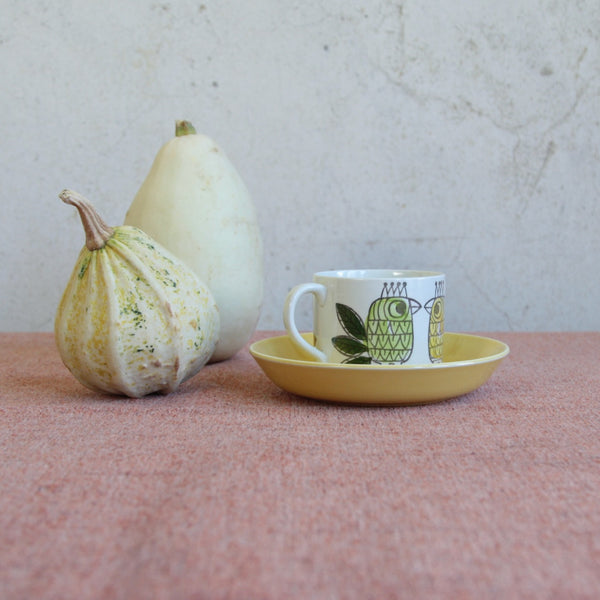 Artistic mood shot showing a collectible Rörstrand porcelain cup and saucer in the King pattern by Marianne Westman — a charming 1960s Swedish design classic. The rare set is sat amongst two pumpkin gourds. 