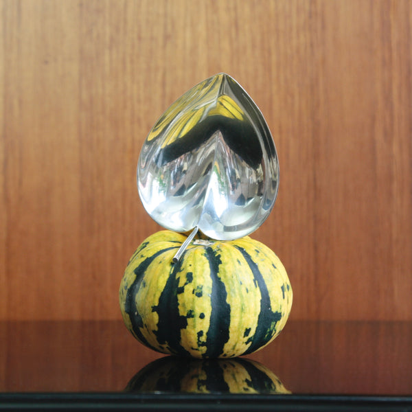 Fun mood shot showing a 1956 Tapio Wirkkala silver leaf-shaped bowl for Kultakeskus,stood atop a green and yellow gourd. The still life emphasises the  elegant sculptural design of the Finnish silver.
