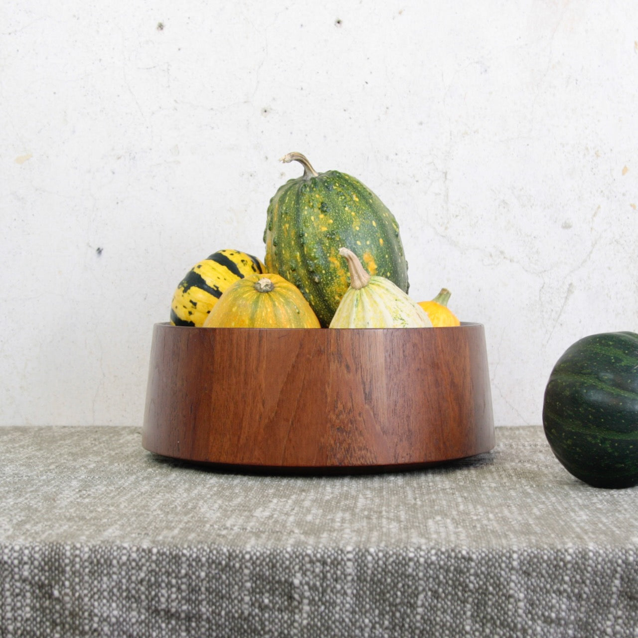Jens Quistgaard wooden teak bowl with gourds on a textured fabric surface. This collectible Dansk Designs item and many others for sale in the UK from Scandinavian design gallery Art & Utility.