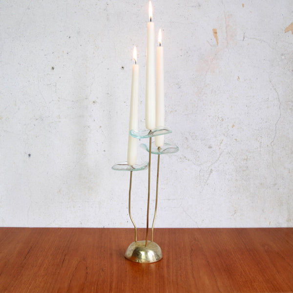 Sculptural Scandinavian candle holder with three flower-shaped brass and glass heads. The candles are lit.