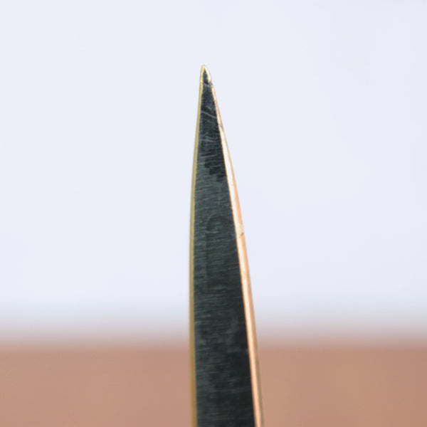 Close-up of a black patinated Walter Bosse letter opener. The design has an owl and is on a blurred background.