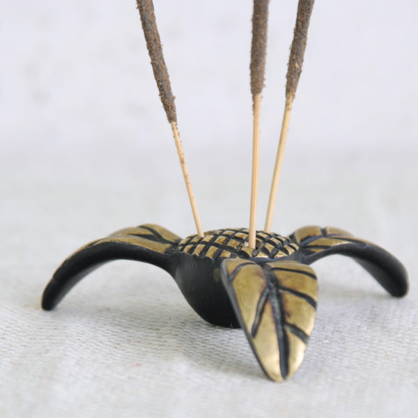 Decorative incense holder with black and gold design on a white background. Rare Walter Bosse brass incense holder, exotic flower form, 1950s Vienna. Available in the UK from design gallery Art & Utility.