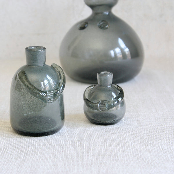 Artistic mood shot showing a group of 3 rare Erik Höglund Carborundum glass bottle vases for Boda, featuring applied arms and a glittering, speckled surface created through experimental silicon carbide infusion.
