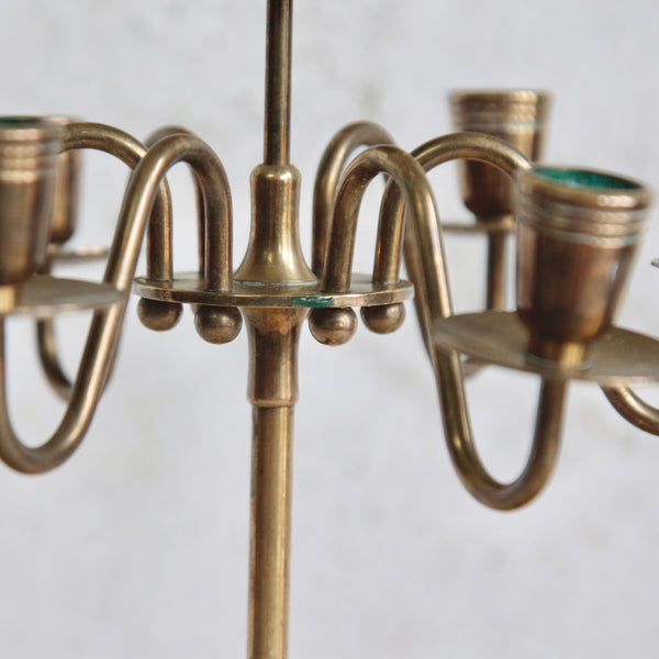 Detail of the central part of a tall Swedish brass seven-headed candelabra, 1950s. Streamlined design with sculptural arms, ideal for Scandinavian décor lovers.