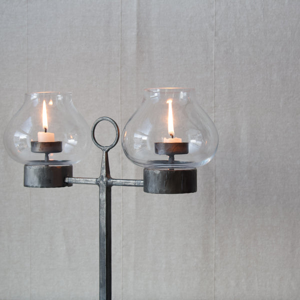Detail showing how two lit candles sit within bulbous glass shades on this mid century swedish candelabrum designed by Bertil Vallien.