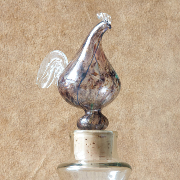 Zoomed in image of a speckled purple glass Rooster. This is the stopper of an ealry "Kukkopullo" or “Rooster bottle” by Kaj Franck for Nuutajärvi Notsjö, Finland. Signed 1960.