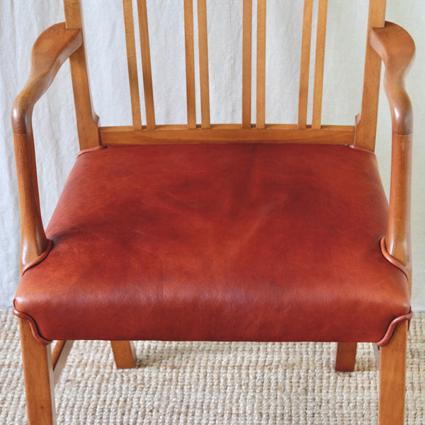 Zoomed in image of red leather upholstered seat on an Ole Wanscher Model 1675 beech carver chair for Fritz Hansen, photographed for UK design gallery Art & Utility.