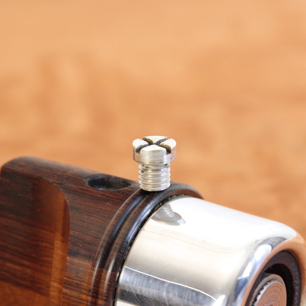 Close-up of silver plated metal screw on top of a Danish mid-century pepper mill in rosewood, designed by Jens Quistgaard and produced by Dansk Designs.