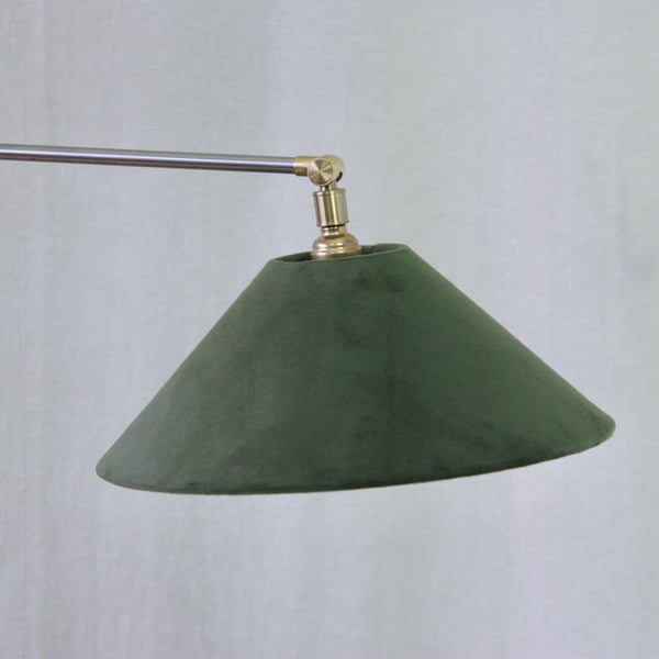 A dark rich green velvet fabric lampshade hanging from a brass and silver metal Esben Klint Model 319 Danish Modern reading lamp.