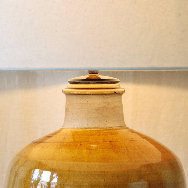 Detail of a Nils Kähler stoneware lamp showing the unglazed neck against the glossy mustard-yellow ochre glaze.