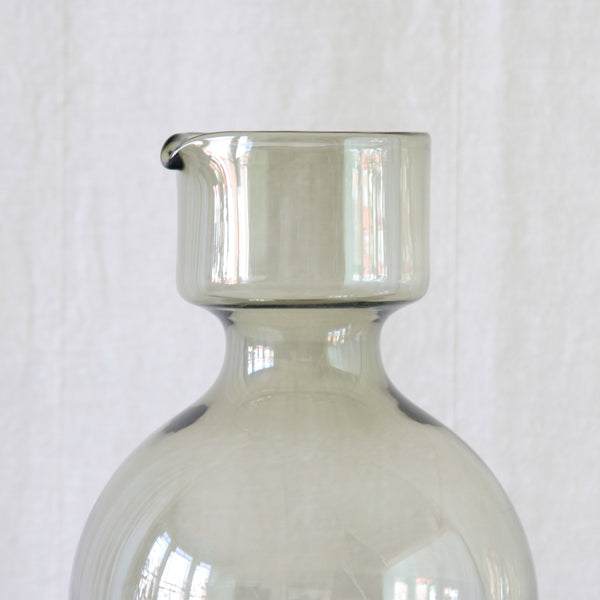 Detail of top half of smoke grey coloured glass pitcher forming the bulbous lower section of Kaj Franck's Kremlin Kellot stacking juice set.