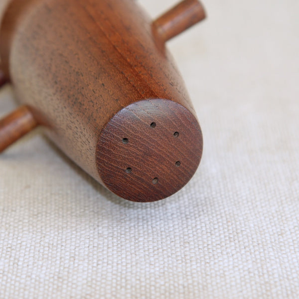 Close-up of a wooden pepper grinder on a beige fabric background. Mid-century Jens Quistgaard salt and pepper mill for Dansk Designs, collectible Danish modern design classic