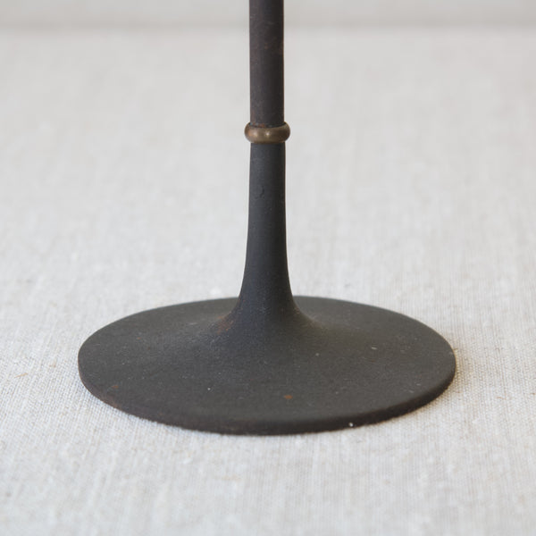 Zoomed in image of the sandblasted cast iron trumpet shaped circular foot on a tall slender Jens Quistgaard candlestick.
