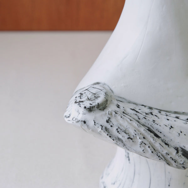 Close-up of a white marble-like porcelain sculpture with intricate carvings on a plain background. Mid-century modern Greek Head bust by Susan Parkinson, for sale in the UK from design gallery Art & Utility, reflecting postwar optimism.