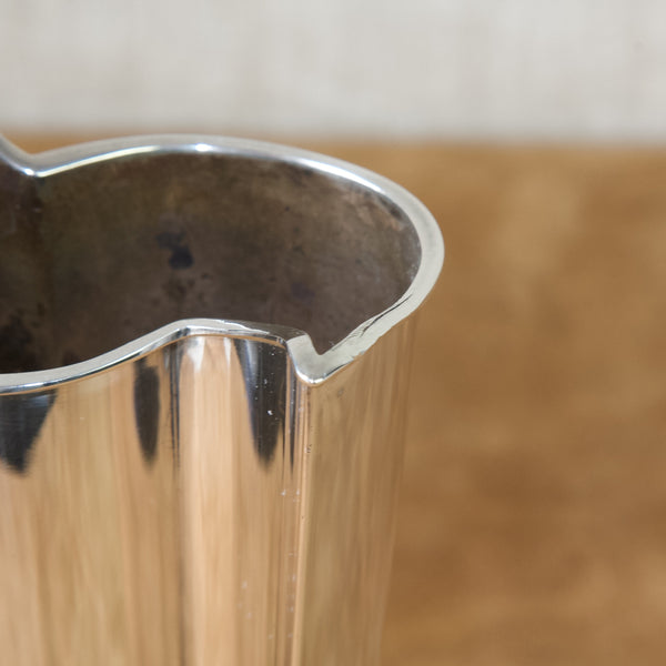 Zoomed in image showing a small tear in the lip of a silver vase by Tapio Wirkkala. The tear has been repaired but the split can still be seen.