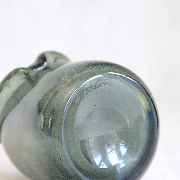 Detail of signature on an Sculptural Carborundum glass bottle by Erik Höglund for Boda, featuring applied arms and a subtly iridescent speckled surface.
