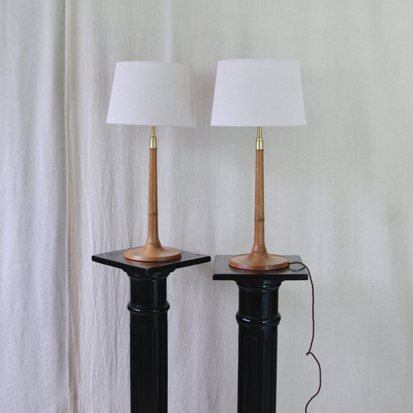 Pair of collectable Le Klint table lamps by Esben Klint in solid oak and brass, with tall architectural forms designed for a sideboard or console.
