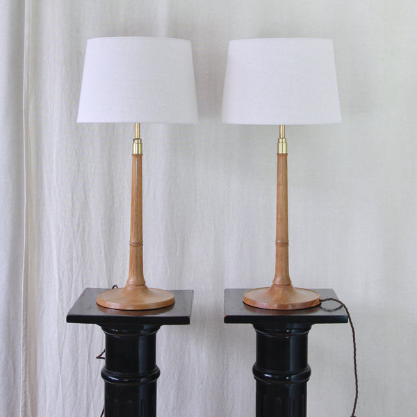 Pair of Esben Klint Model 301/27 table lamps in solid oak and brass, designed for Le Klint, Denmark, circa 1950. Lights are fitted with natural linen drum shades.