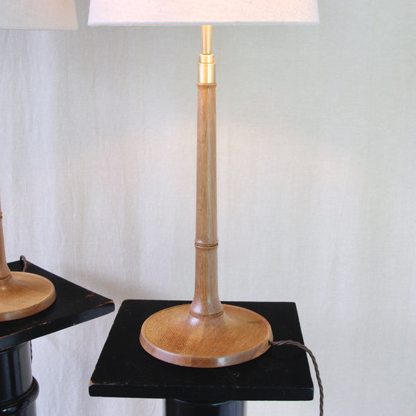 Esben Klint 301/27 lamp viewed head on, showing its continuous flowing profile from the circular oak base to the brass fitting. The natural oak wood column has a beautiful honey colour and lively grain.