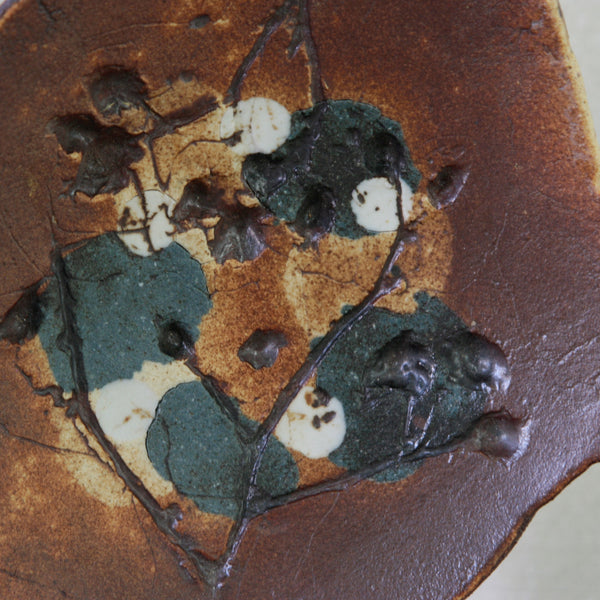 Detail of decoration on ceramic dish by Francesca Mascitti-Lindh, with expressive botanical lines worked across contrasting blue, white and brown clays.