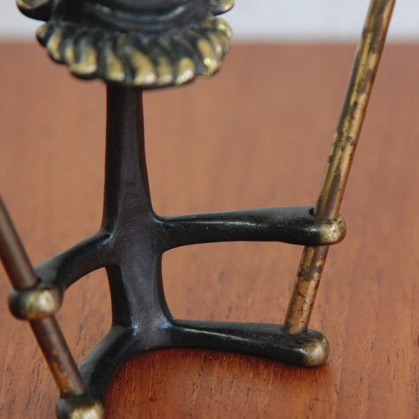 Close-up of a functional and decorative Walter Bosse brass gnome, bonsai accessory with spade and rake.