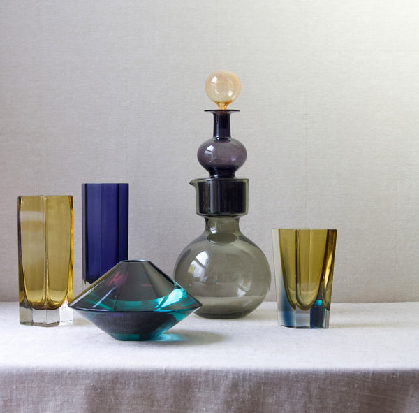 Group shot of five pieces of collectible MidCentury Modern glass by Nuutajärvi Notsjö. All 5 designs are by Kaj Frank. The rarest examples are the flying saucer shaped item, named UFO, and the tall stacking decanter, named 'Kremlin Bells'. For sale in the UK from London based design gallery Art & Utility. Shipping offered to Japan, Singapore, Hong Kong, Taiwan, etc.