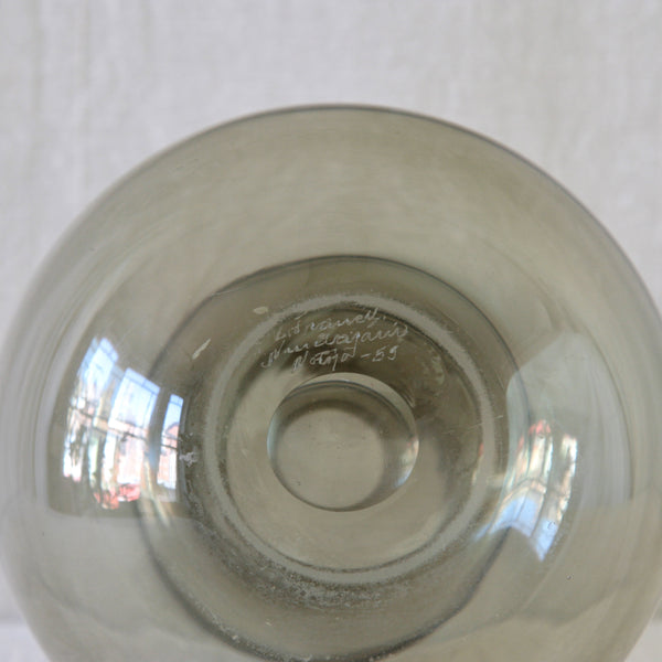 Close-up of the bottom of a smoke grey glass pitcher with handwritten signature inscription. The makers mark on this Kremlin Kellot /Kremlin Bells decanter and pitcher set reads; K. Franck, Nuutajärvi Notsjö, 1959.