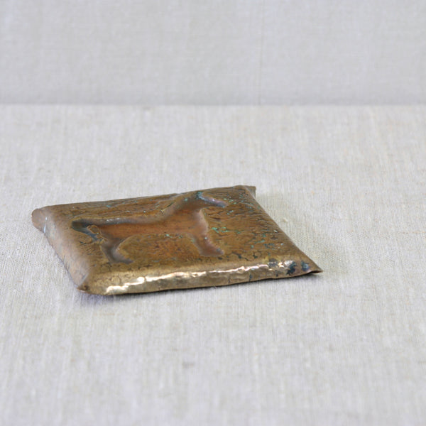 Back of Hammered brass dish with repoussé horse decoration, the raised equestrian motif surrounded by a heavily textured hand-worked surface.