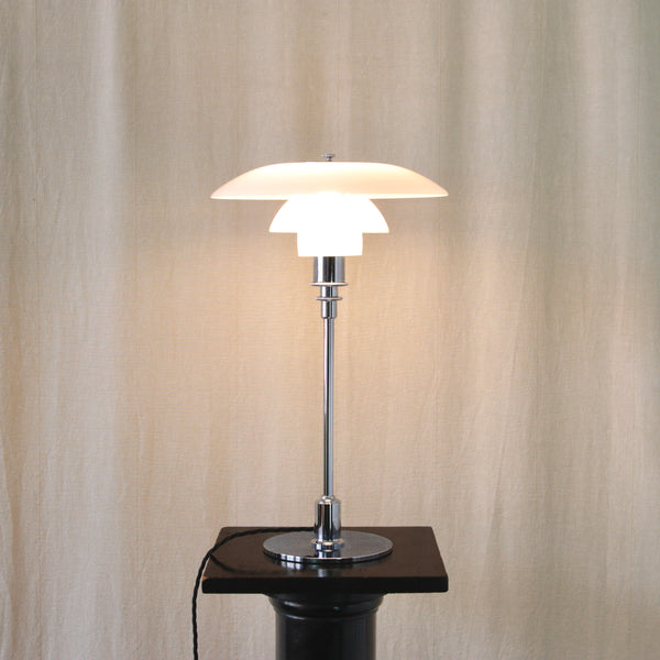 Side view of a 1970s Poul Henningsen Type 23405 table lamp, illuminated, showing the distinctive tiered profile of the PH 3/2 shades.