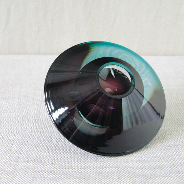 Kaj Franck KF 235 Flying Saucer viewed from above, revealing the circular geometry, hollow centre and changing purple and blue tones within the glass. The photo also shows the hand written etched signature dated 1958.