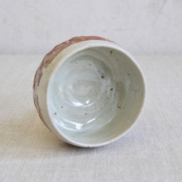 Decorative tea bowl by Phil Rogers with impressed lattice texture and soft, varied wood-fired colours. Internally the bowl is glazed with a thick nuka glaze that contains fallen ash from the wood firing. 