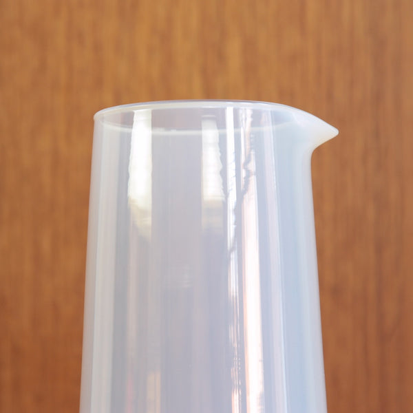 The Jacob Bang milk-glass carafe photographed to show its sculptural conical form and hand made pouring lip inspired by scientific glassware.