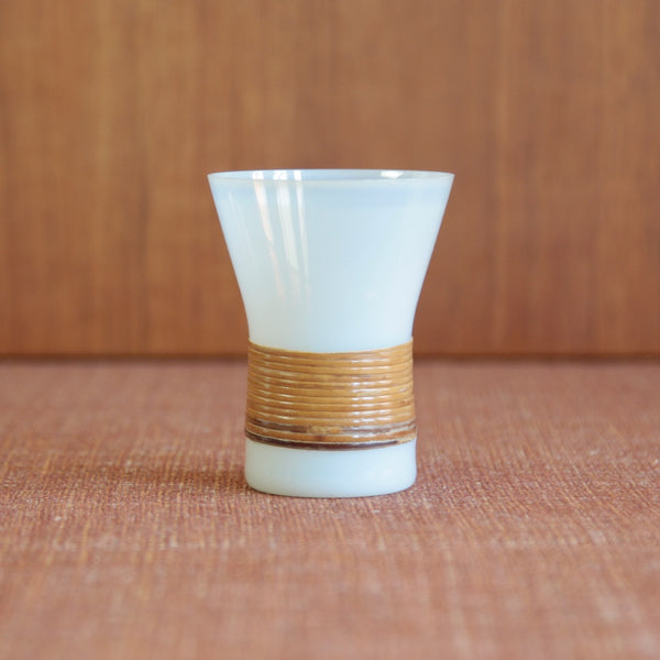 A close view of 1 cup with rattan-wrapped waist designed by Jacob Bang, reflecting Danish mid-century craftsmanship. Rare and collectible Holmegaard design.