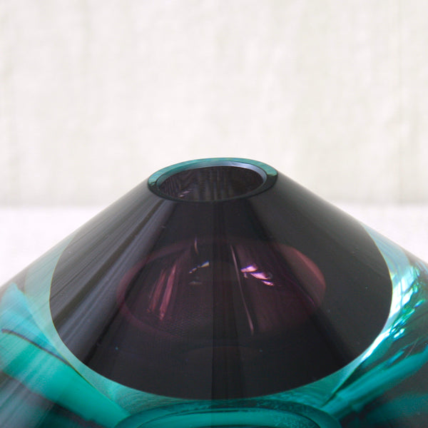 A close-up of a translucent glass vase with a conical top. Rare Kaj Franck KF 235 Finnish art glass in deep sea blue and Tyrian purple, with light refracting through the thick sculptural Flying Saucer form.