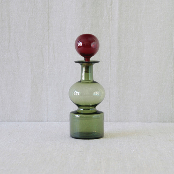 A green decanter with red ball stopper, the top section of a Kremlin Bells juice set by Kaj Franck for Nuutajärvi Notsjö, the celebrated Finnish glass design associated with Franck's 1957 Milan Grand Prix.
