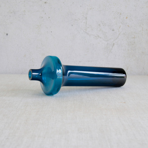 Artistic mood shot showing a Helena Tynell Riihimäki Katedraali vase laying on its side. This slender vintage hand-blown Finnish glass art object is highly collectible and available for worldwide shipping.