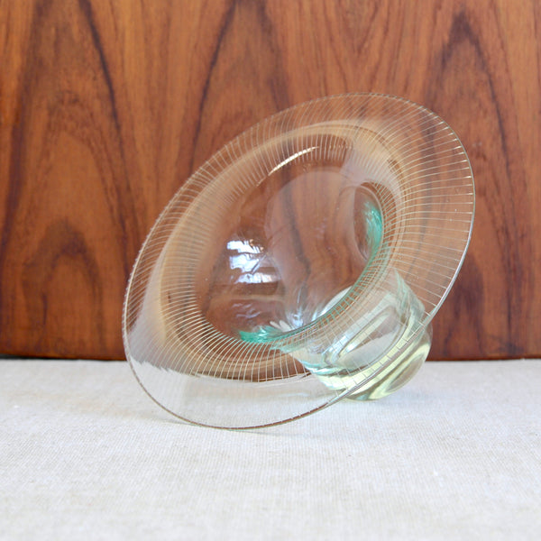 Lead image, head on shot of a Scandinavian hand blown glass bowl by Helena Tynell Kaulus laying on its side. The collar shape refined mid century collectible is incised with delicate lines.