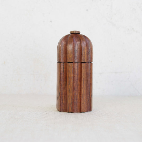 Wooden pepper grinder on a light background. Jens Quistgaard teak pepper mill with transitional metal and plastic grinder.