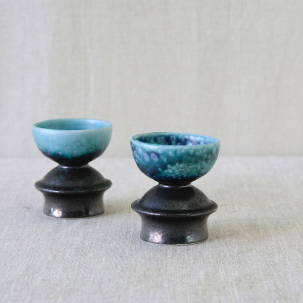 Pair of stoneware candleholders by Liisa Hallamaa for Arabia Finland, with chocolate-brown exteriors and vivid blue glazed bowls.